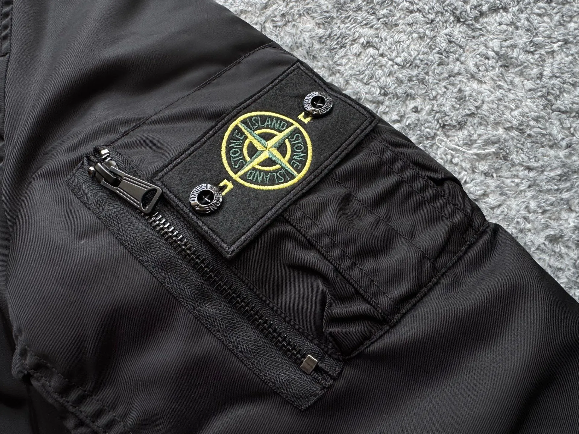 P360 Stone lsland Stone Island Medal Aviator Cotton Jacket The outer fabric is made of MA-1 flight nylon, which is a material specially used in flight and aviation. Flying nylon is a fabric specially used in flight and aviation. It is rarely used in ordinary clothing. The density of flying nylon is very high, so it is windproof and waterproof. When rain falls on the surface of the clothes, it will not penetrate immediately, but will form a small water droplet and slide off. This performance is a requirement for the development of modern jet technology. Because it is assumed that the pilot got caught in the rain before getting on the plane, he entered the cabin covered in rainwater. When flying at high altitude and at high speed, in a cabin without an environmental control system, water droplets will freeze on the pilot's body 2. Knitted baseball collar MA-1 uses a knitted collar. The collar is made of wool and can be snug around the neck and very warm. 3. Metal zippers We have very strict requirements on zippers, including smoothness and size. There was no zipper on the market that met the requirements, so we asked a zipper factory to customize a strong and durable metal zipper.  4. Double-threaded knitted cuffs The cuffs are made of double-threaded knitted fabric, narrow at the front and wide at the back. The narrow part can be tightened around the wrist to prevent wind from entering. The wide part has enough space when wearing multiple pieces under winter Color: Black Dark Army Green Size: M L.